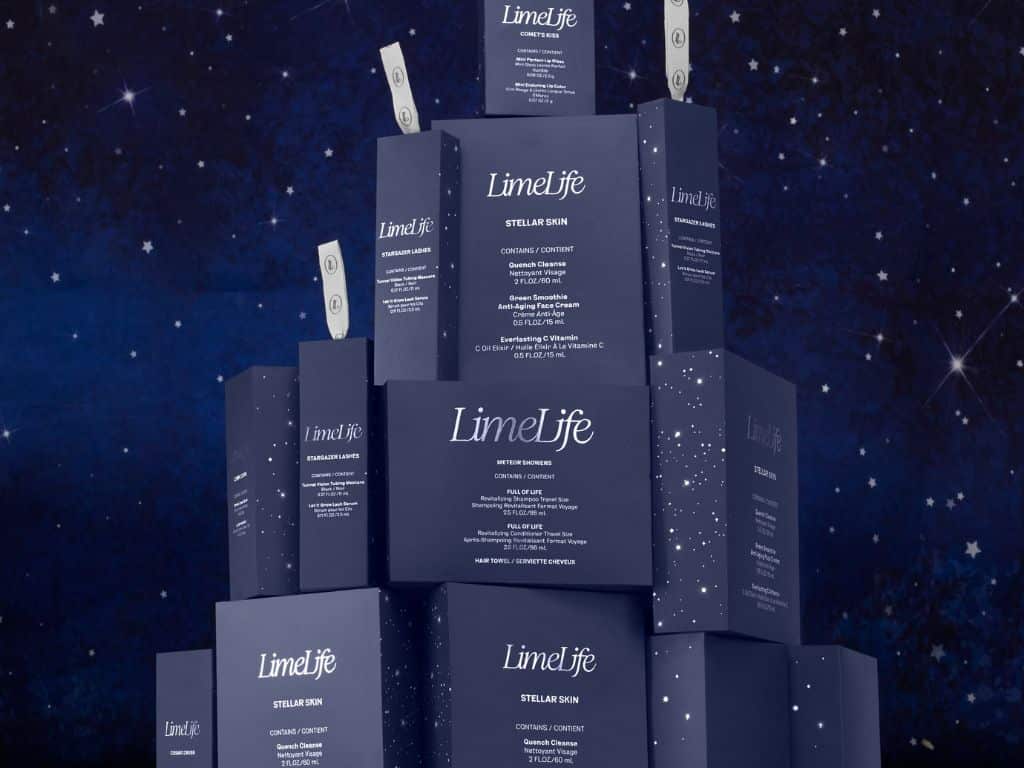LimeLife holiday 2025. A pyramid of dark blue LimeLife skincare boxes with white text and star patterns is stacked against a starry night sky background. Some boxes have dollar bills peeking out from the top.