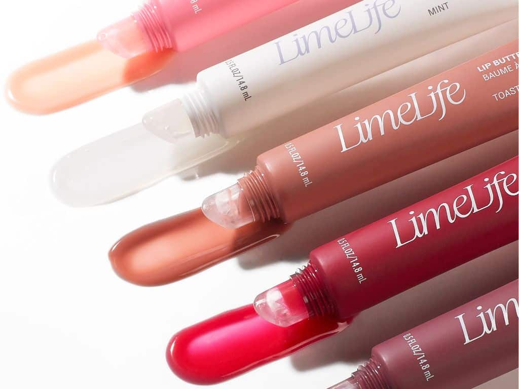 Five LimeLife lip butters in various shades, arranged diagonally with clear caps removed to show the product colors, ranging from nude and pink to red.