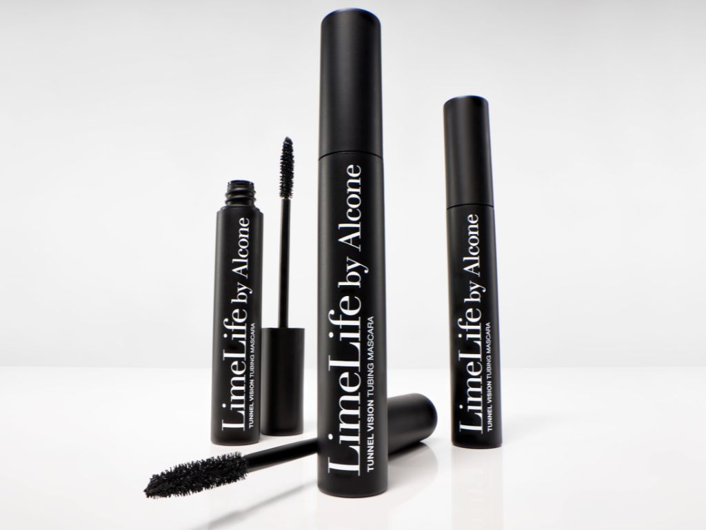 Three black tubes of LimeLife by Alcone Tunnel Vision Fiber Mascara are arranged on a white surface, with one tube open and the mascara wand lying in front, showing the bristled brush. LimeLife Tubing Mascara